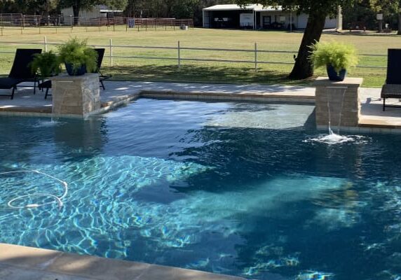 A pool with water jets and a fence